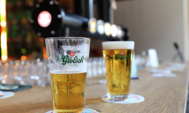 Twee vaasjes grolsch op de bar in de horeca met een tap op de achtergrond